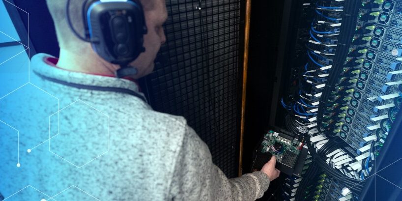 man with headphones on standing next to computer terminal