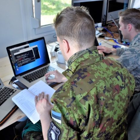 soldier reviewing notes while in front of laptop computer